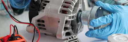 Master repairman diagnosing breakdown of car generator using tester closeup