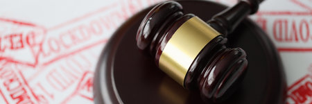 Judge gavel lying on documents stamped with covid19 red seal closeup