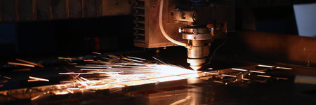 Sparks fly out of automated machine, metal processing laser on metallurgical backgroundの写真素材