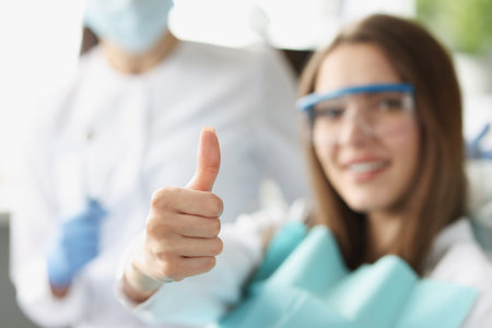 A woman at the dentist shows a thumbs up gestureの写真素材