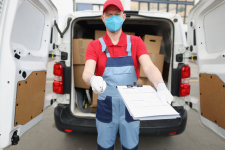 The delivery man holds out documents for signatureの写真素材