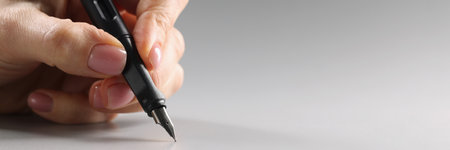 Female fingers hold a black fountain pen, close-upの写真素材