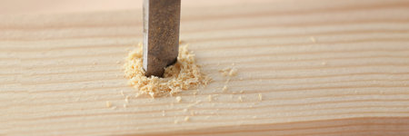 Drill instrument making hole in wooden plank, wood chips on surface