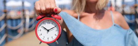 Smiling female tourist holding an alarm clock on sea pierの写真素材