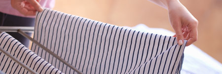 Woman after washing hangs clothes on dryer to dry