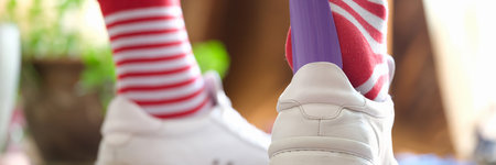 Person puts a shoehorn into sneakers closeup