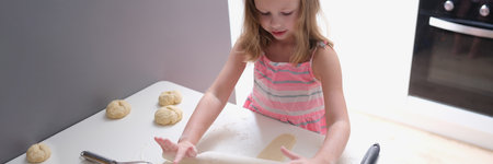 Child girl with rolling pin for baking cookies for dough
