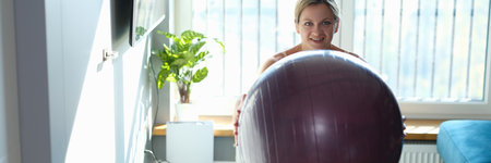 Sporty smiling woman doing exercises with fitness ball at homeの写真素材