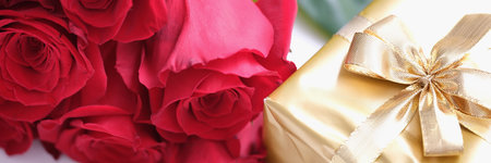 Gift box for Valentine Day tied with golden satin ribbon bow and beautiful rosesの写真素材