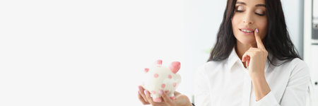 Woman hold piggybank, think of better way to use money, saving up for futureの写真素材