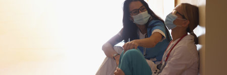 Surgeon in hospital corridor with communicates with doctor sitting on floorの写真素材