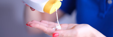 Woman pours body care lotion or sunscreen from bottle into handの写真素材