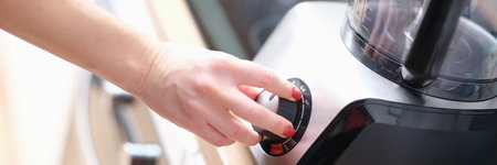 Woman hand presses start of food processor closeup