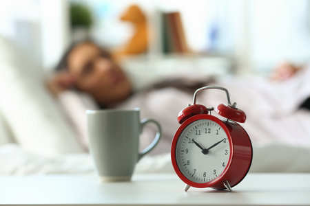 Red alarm clock at ten oclock and sleeping womanの写真素材