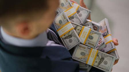 Businessman carrying many bundles of dollar bills closeup
