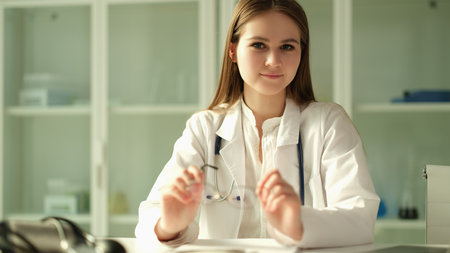 Portrait of young woman doctor with glasses in her hands in clinicの写真素材
