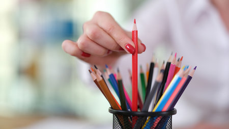Female hand taking out red pencil from glass closeupの写真素材