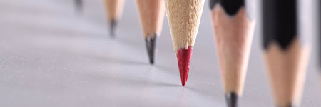 Red pencil stands out from crowd of many identical black pencils