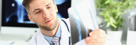 Male doctor examines x-ray of leg and arm in clinic