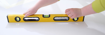 Working hands check evenness of wall with special tool for measuring level
