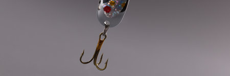 Fishing tackle with bait and hook on gray background