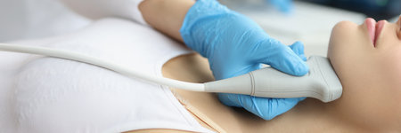 Doctor examining thyroid of female patient with ultrasound scan in clinic
