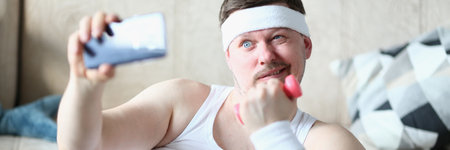 Young man takes selfie with dumbbells in handsの写真素材