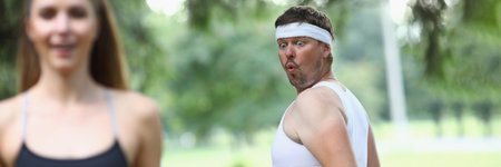 Man is jealous of beautiful running woman and looks at ass in parkの写真素材