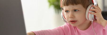 Little girl child in headphones in front of laptop