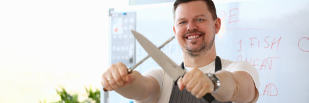 Smiling handsome male cook is holding sharp knifeの写真素材