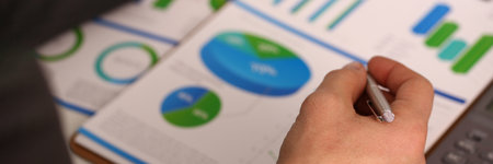 Businessman is holding pen and pointing to marketing chart and is working with financial documentsの写真素材