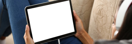 Mockup image of a digital tablet with black screen in hands of woman in headphones