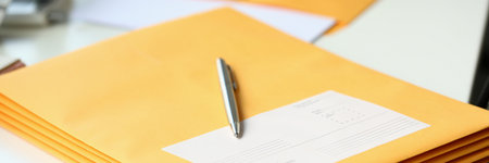 Yellow envelope with business correspondence with pen on desktop in officeの写真素材