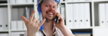 Emotionally cheerful male manager in travel company in swimming goggles is talking on mobile phone at workplaceの写真素材