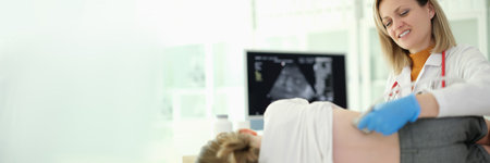 Doctor pediatrician conducting ultrasound examination of kidneys of child in clinicの写真素材