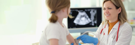 Doctor traumatologist making ultrasound examination of elbows of little girl in clinicの写真素材