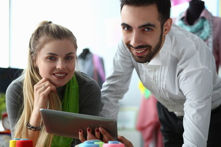 Man and woman tailor and client using touch pad in atelierの写真素材