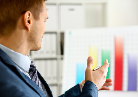 Man in suit point with arm in stats graphの写真素材