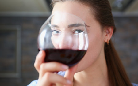 Beautiful woman hold in arms glass of red wineの写真素材