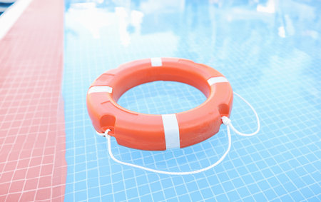 Orange plastic lifebuoy floating in pool closeup