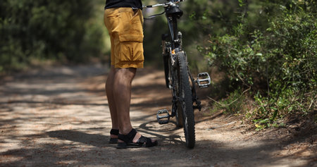 Man standing near mountain bike on path in forest closeupの写真素材