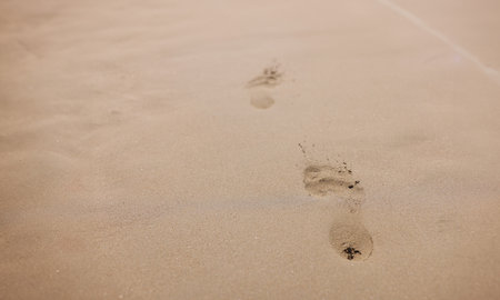 Closeup of footprints from bare feet on sand