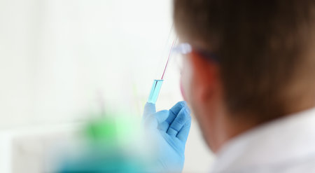 A male chemist holds test tube of glassの写真素材
