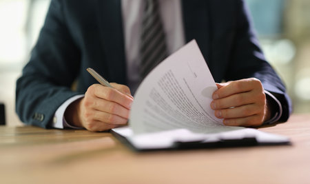 Businessman leafing through documents and signing contract for business deal at work in office closeupの写真素材