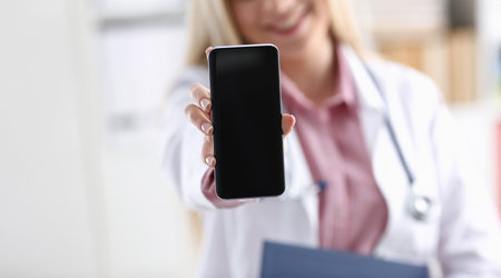 Beautiful female blonde doctor holding smartphoneの写真素材