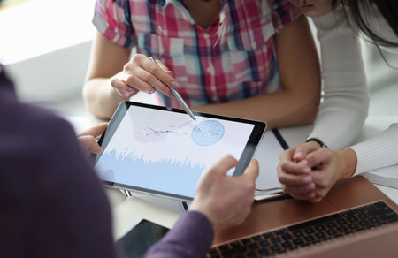 Group of people discussing graph on digital tablet closeup