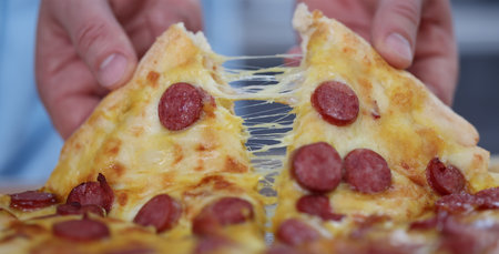 Male hands tearing off slice of hot pizza closeupの写真素材