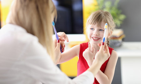 Little girl choosing toothbrush from doctors hands in clinicの写真素材