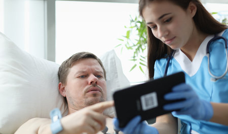 Doctor showing patient data on digital tablet in hospitalの写真素材