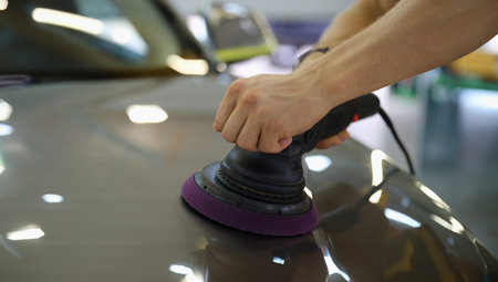 Male hands polishing hood of car with special machine closeupの写真素材